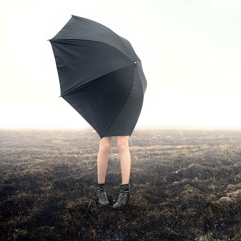 Frau mit schwarzem Schirm bei einem starken Wind